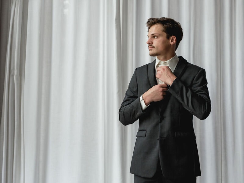 Groom selecting men's formal attire for wedding at Bridal Aisle Boutique — wedding suits Minnesota